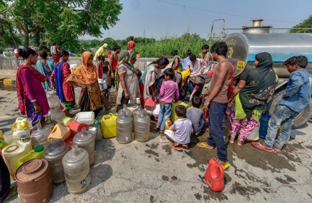 People, not following social distancing guidelnes, carry cans and other containers to collect drinking water from a tanker, during Unlock 4 in East Delhi, Saturday, Sept. 12, 2020. (PTI Photo)